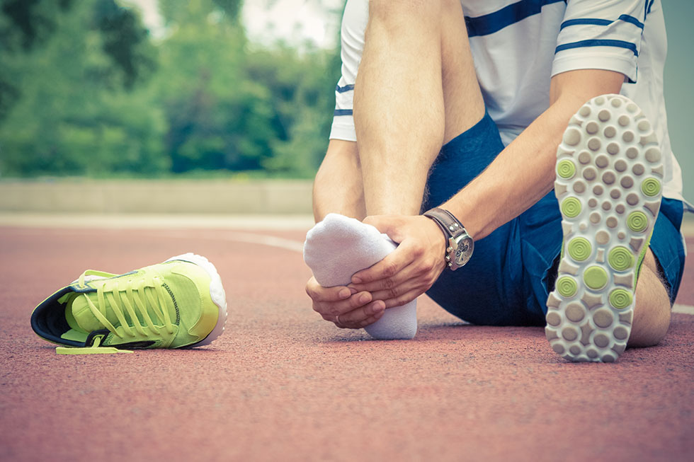 An athlete on a track sitting down in pain, grabbing th