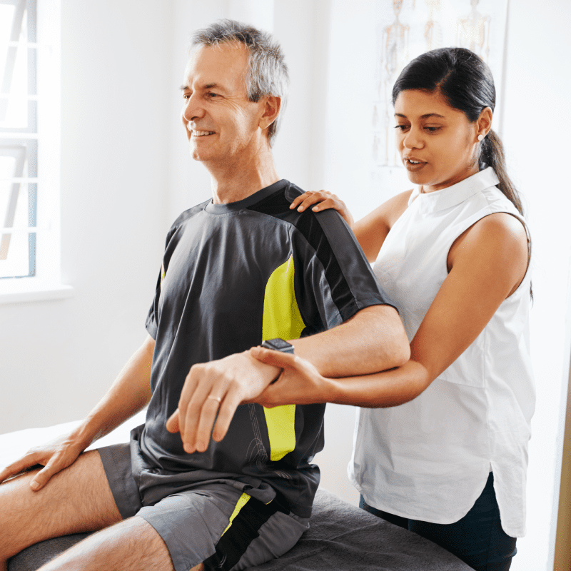 Physical therapist helping patient stretch his shoulder and left arm
