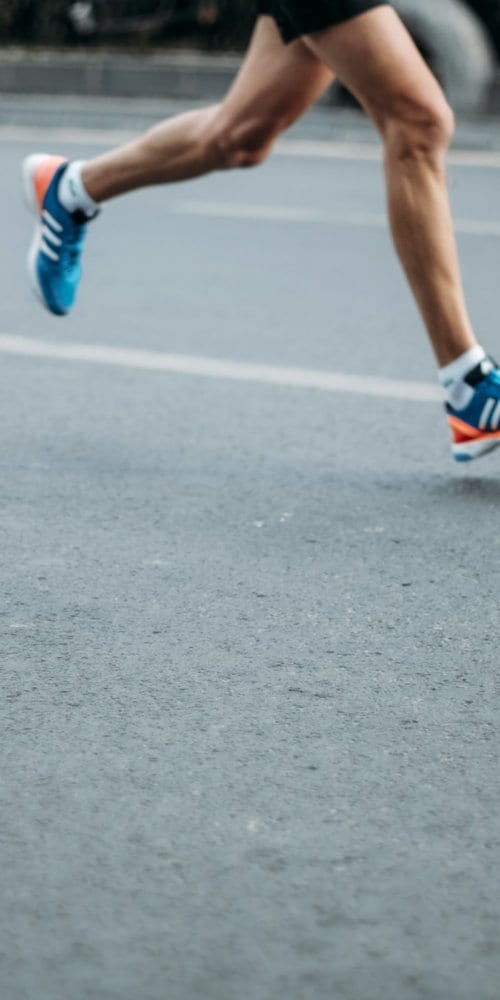 Athlete's legs running on pavement